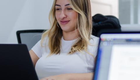 Young woman focused on her laptop screen, working in a modern office environment.