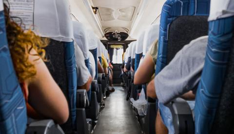 Passengers seated on a bus during a daytime journey, capturing a travel atmosphere.