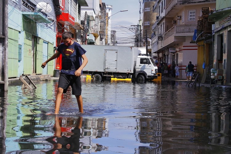 Homem caminha na Rua dos Barés alagadas. Foto: Divulgação/ Semcom