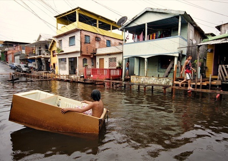 Garoto brinca em casco de geladeira e tem contato com água do Rio Negro durante cheia em Manaus. Foto: Arquivo/ Semcom