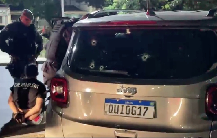Homem preso ao lado do carro crivado de balas - Foto: Divulgação
