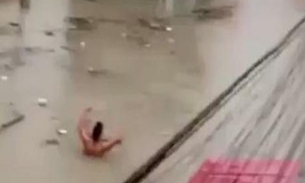 Homens andam com água até o pescoço em rua alagada pela chuva em Manaus