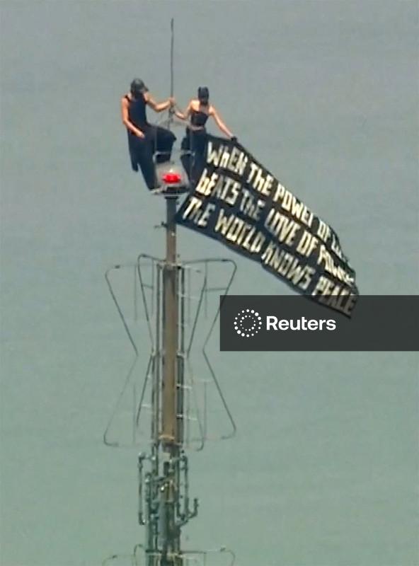 Duas pessoas exibem faixa pela paz mundial no alto do Empire State Building em NY